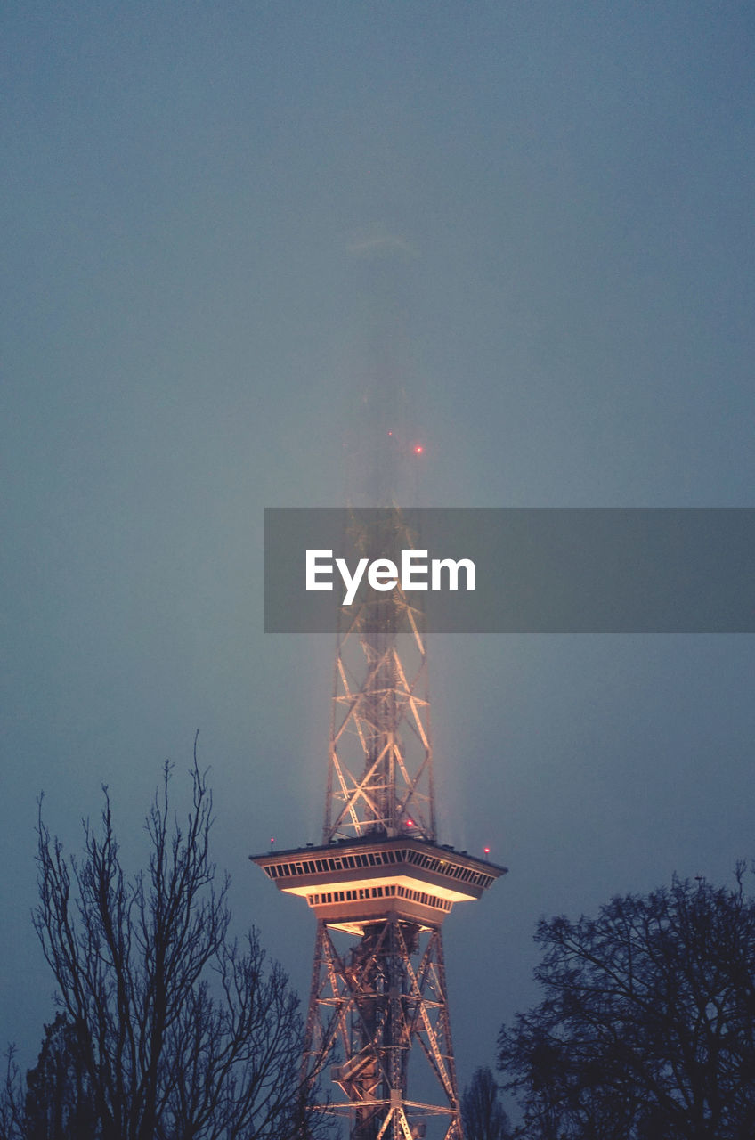 Low angle view of illuminated tower against sky at dusk