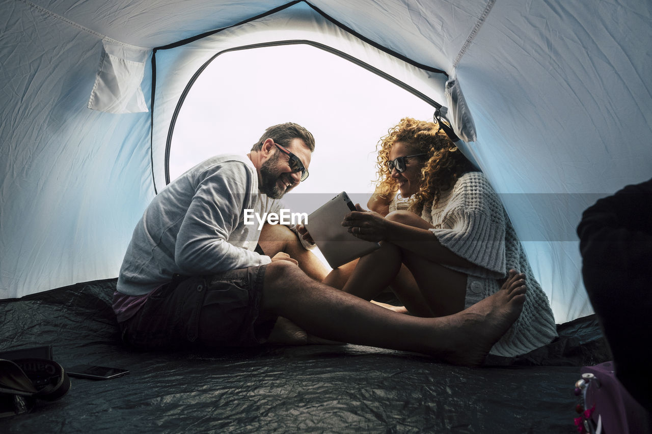 Smiling couple using digital tablet in tent