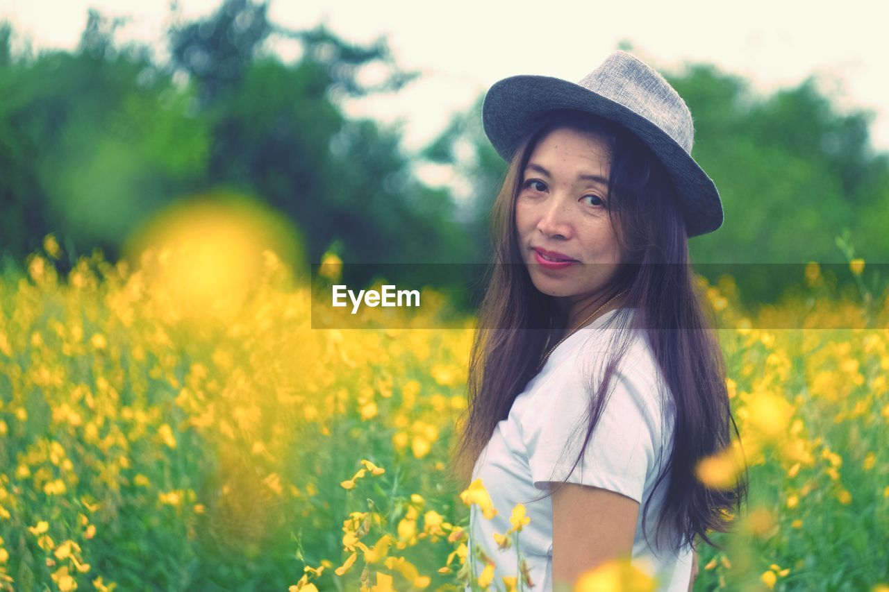 Portrait of beautiful young woman standing on field