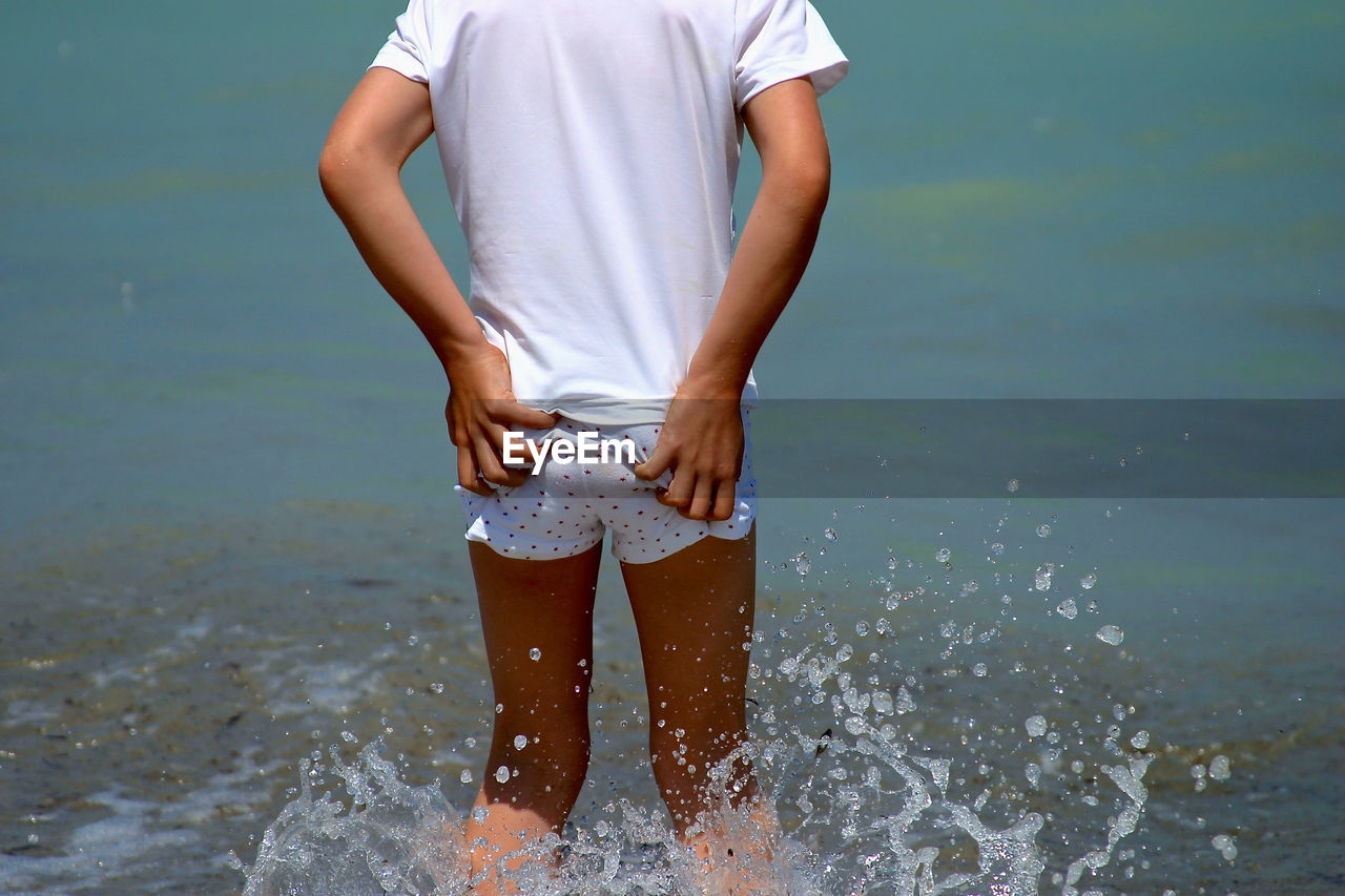 Midsection of kid standing in sea