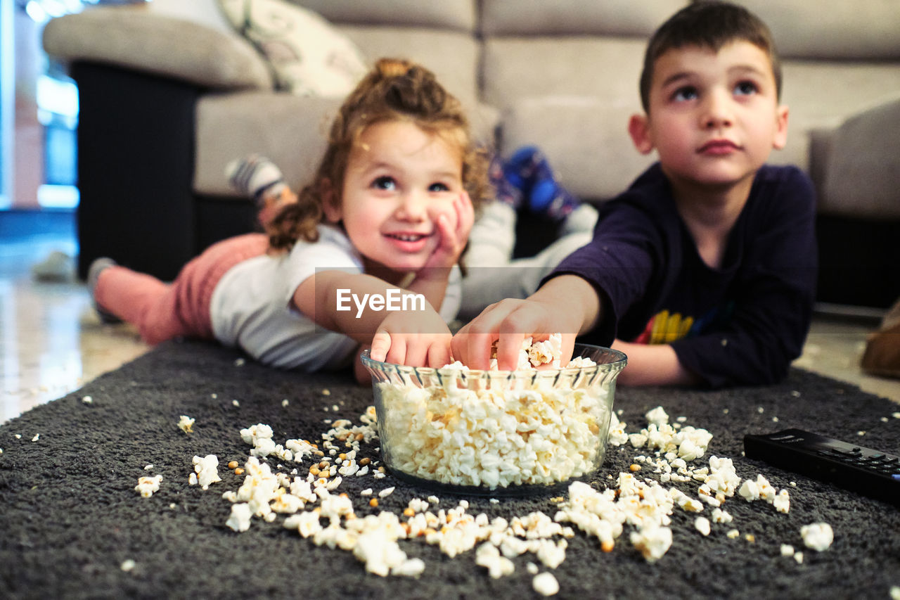 Siblings watching a home movie while eating popcorn