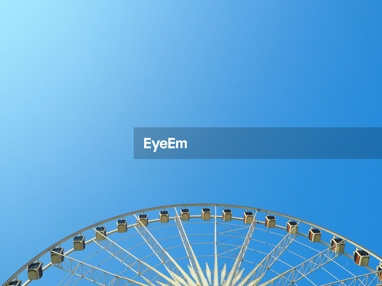 Cropped image of ferris wheel against clear blue sky