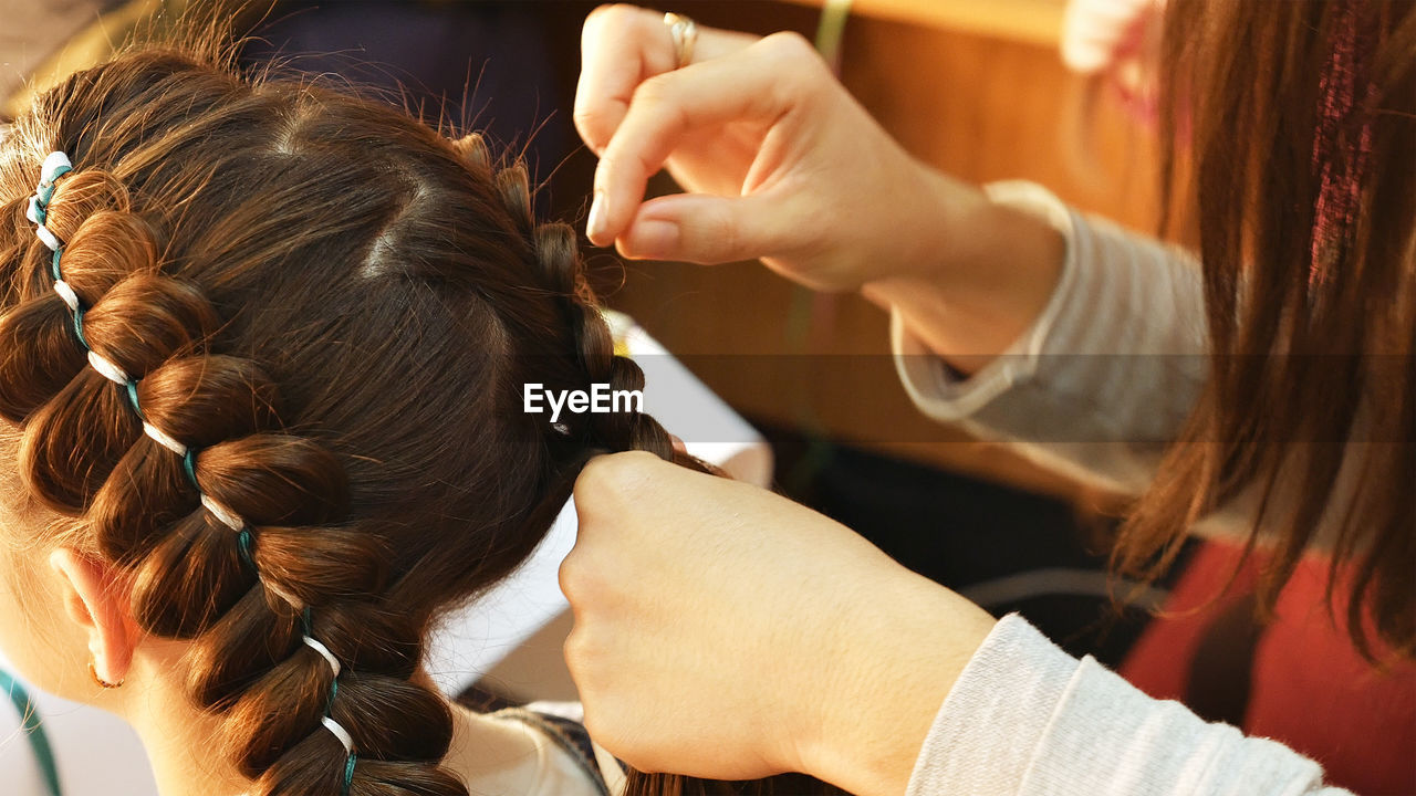 Cropped hands of female hairstylist styling girl hair