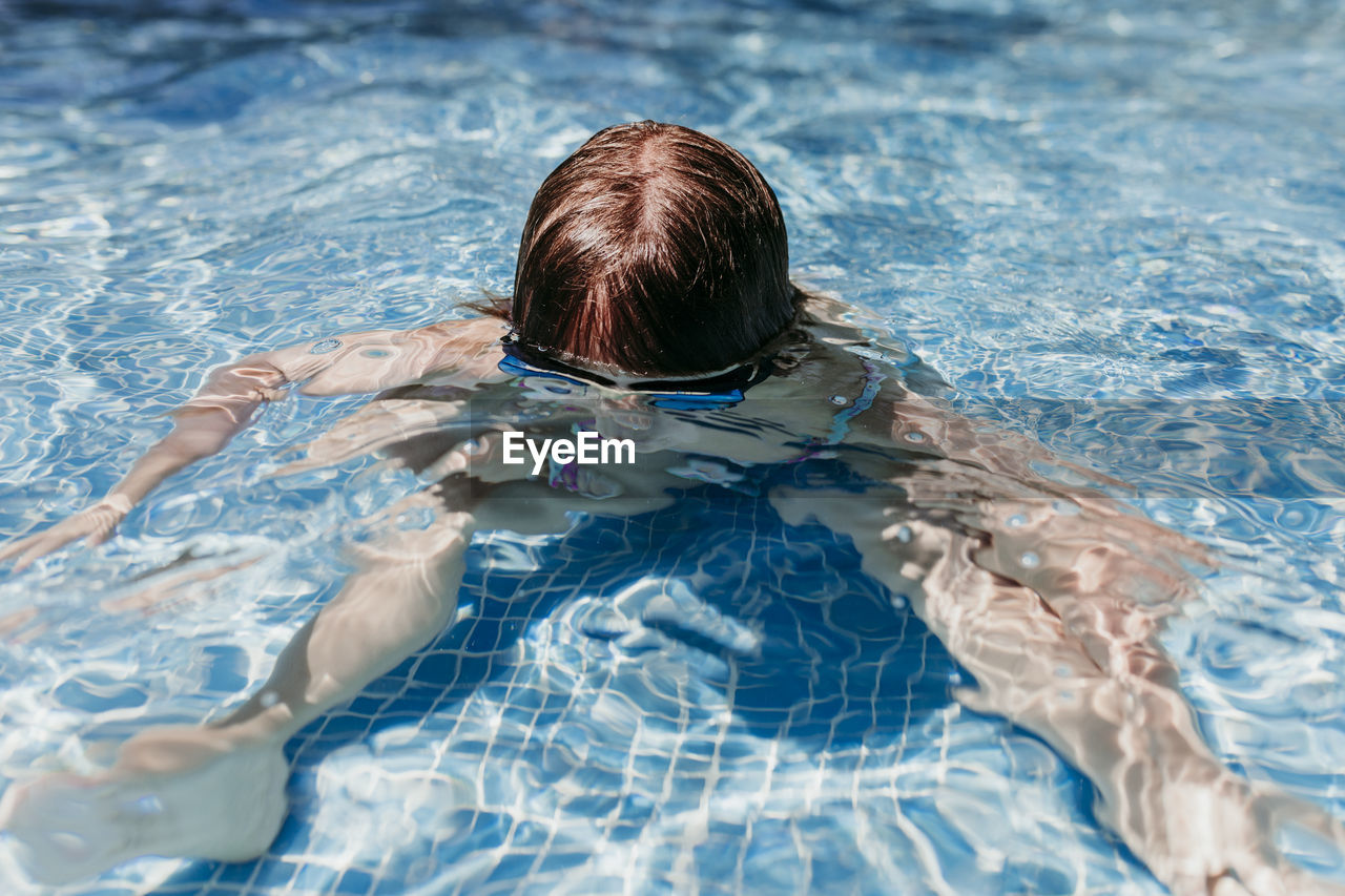 HIGH ANGLE PORTRAIT OF WOMAN SWIMMING IN POOL