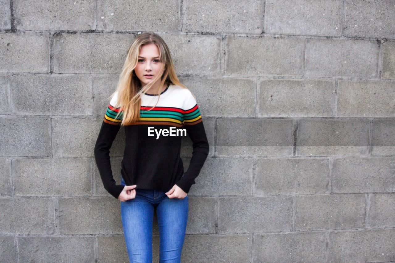 Portrait of young woman leaning on wall