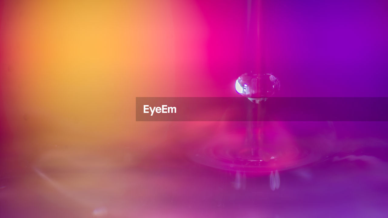 CLOSE-UP OF WATER DROP FALLING ON PINK GLASS