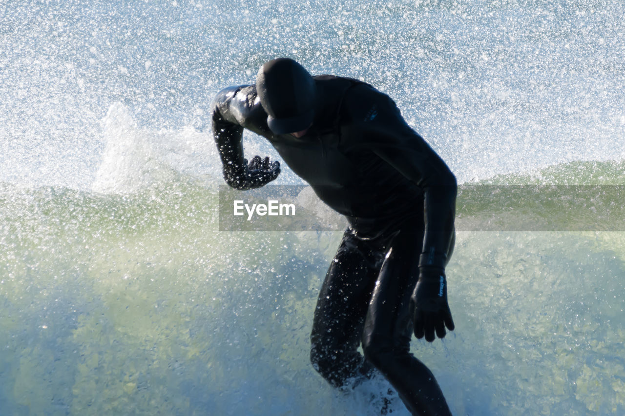 Man wearing wetsuit surfing in sea