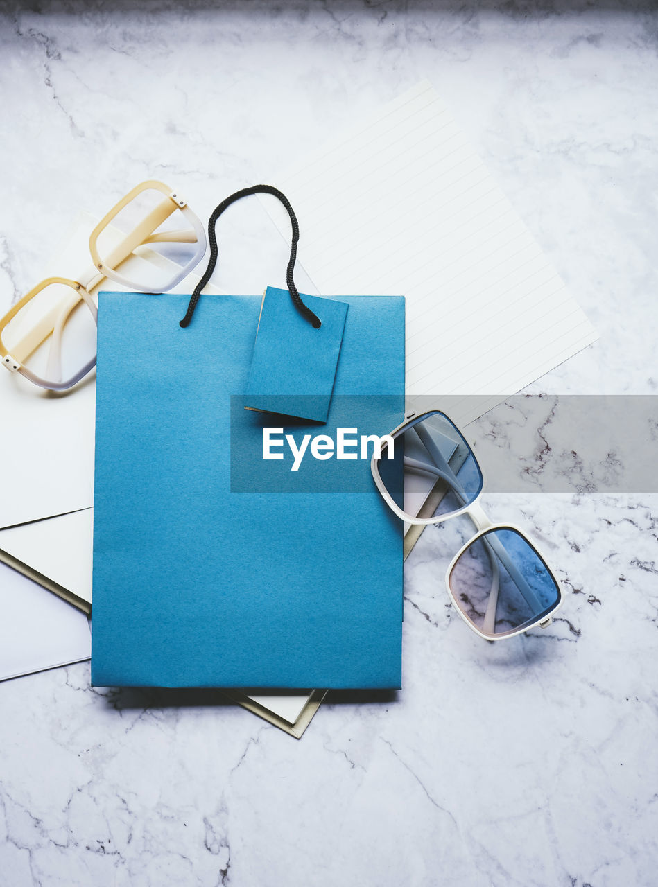 blue, glasses, eyeglasses, turquoise, no people, indoors, fashion accessory, studio shot, high angle view, still life, handbag, paper, fashion, copy space, sunglasses, bag, group of objects