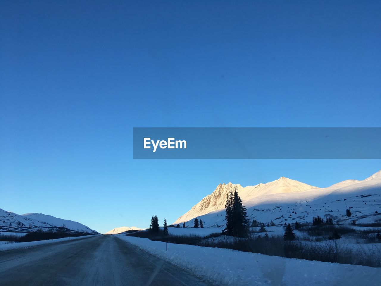 ROAD BY SNOWCAPPED MOUNTAIN AGAINST CLEAR BLUE SKY