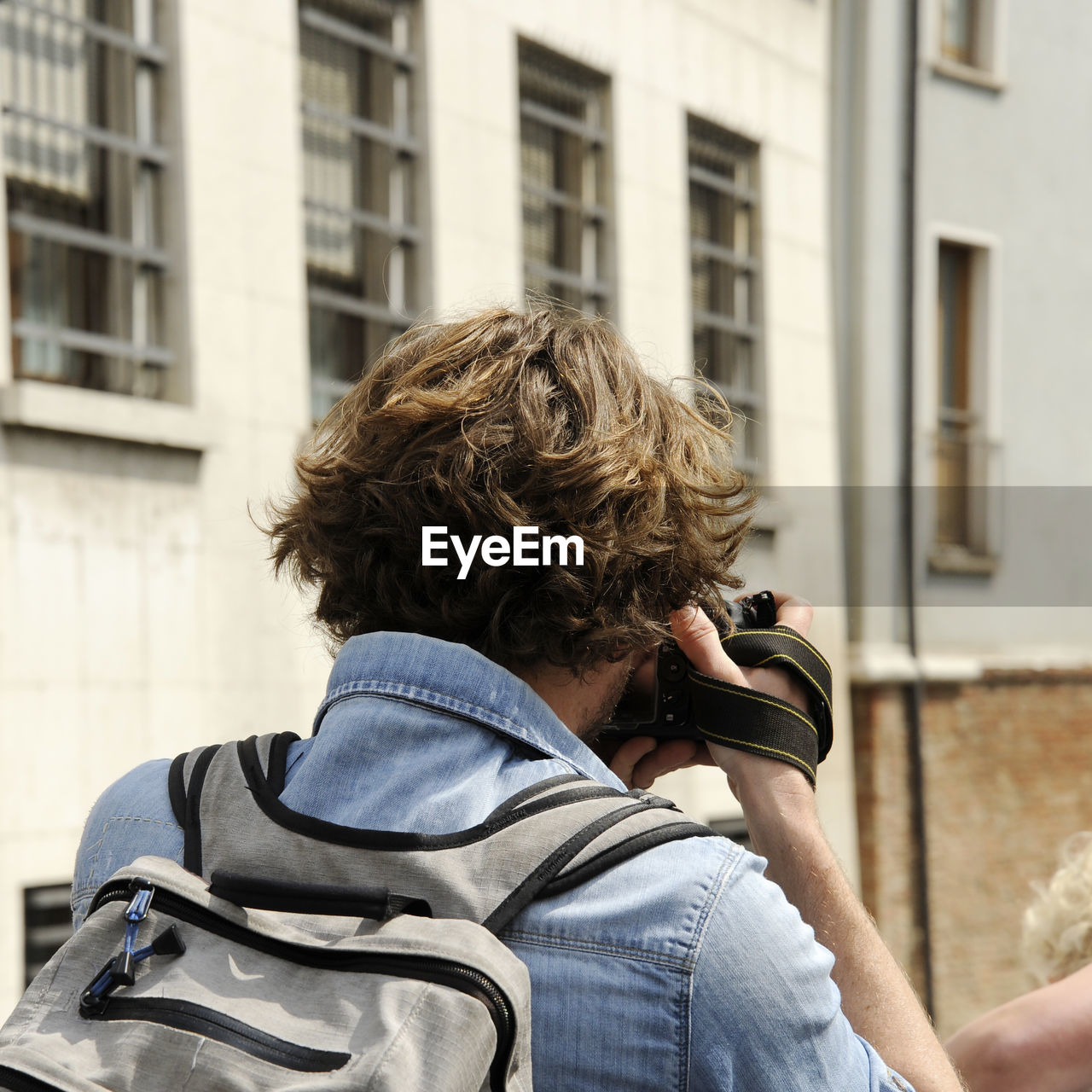 REAR VIEW OF MAN PHOTOGRAPHING AGAINST SKY