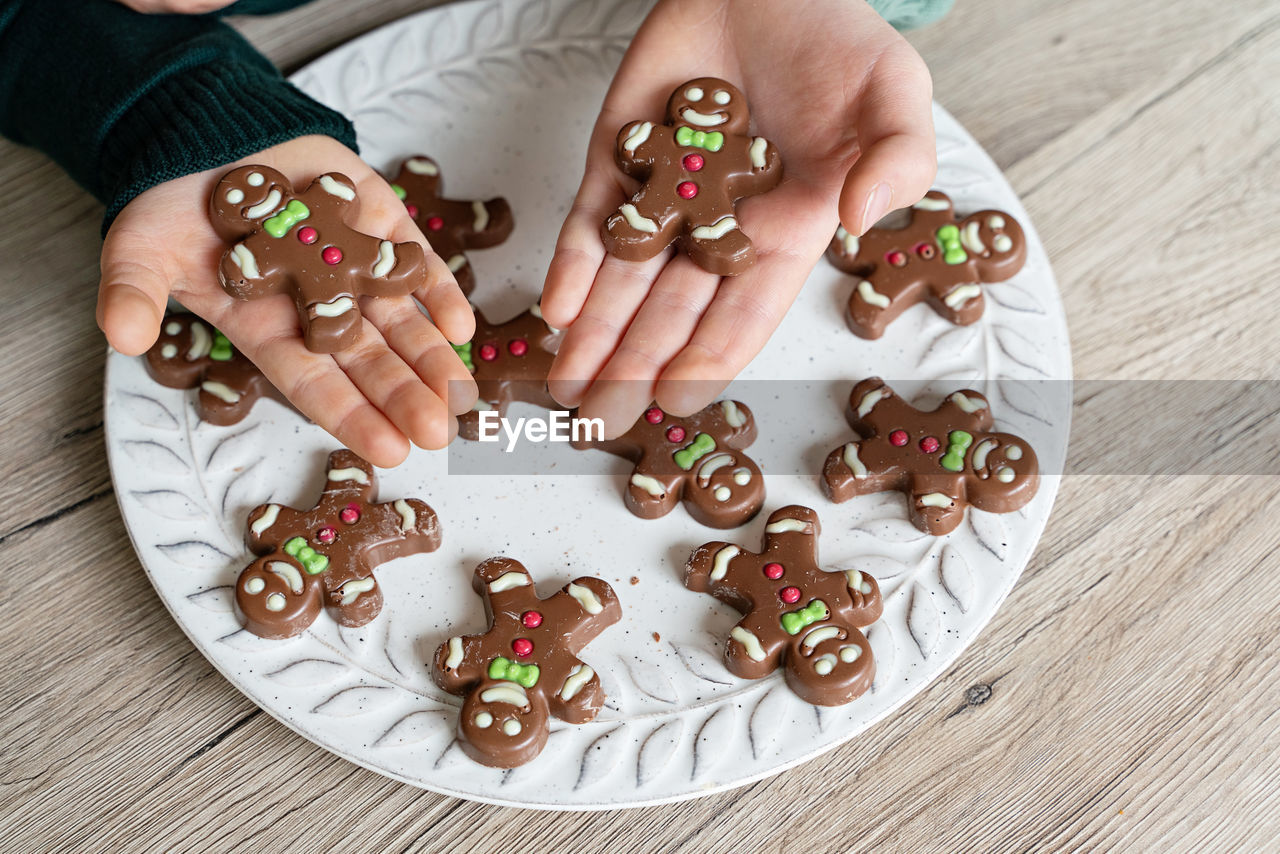 Cropped image of boy holding gingerbread cookies at home