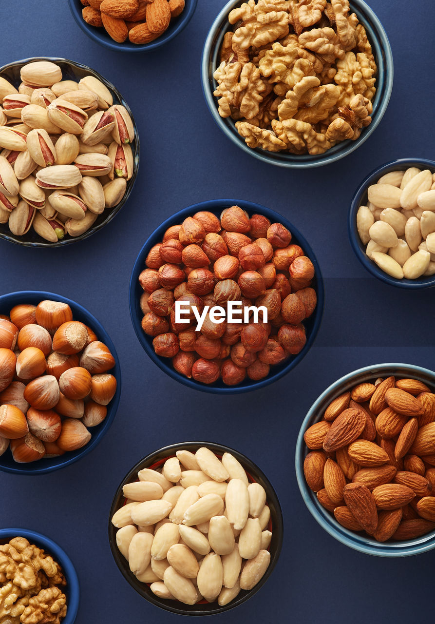 Various nuts in a bowls on a blue background viewed from above. top view