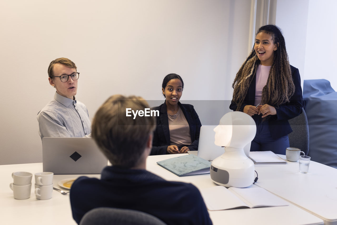 Business people discussing robot voice assistant during meeting