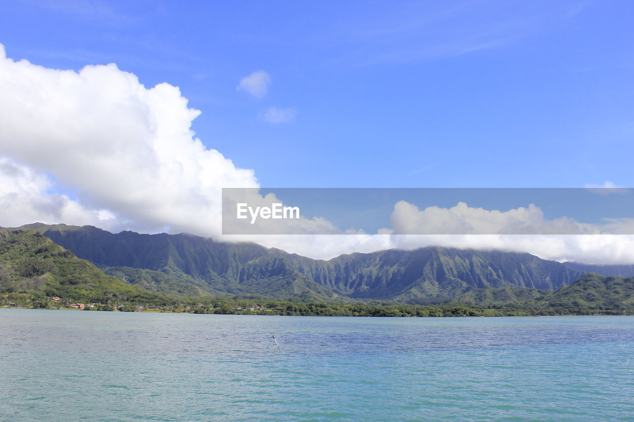 SCENIC VIEW OF SEA AND MOUNTAINS AGAINST CLOUDY SKY