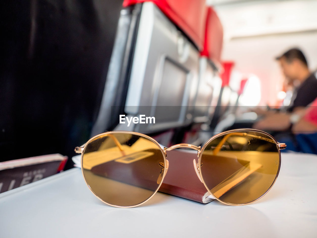 CLOSE-UP OF SUNGLASSES WITH REFLECTION ON GLASS TABLE
