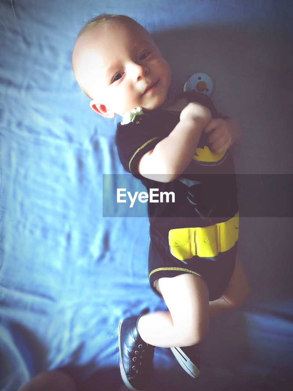 Directly above portrait of baby boy lying on bed