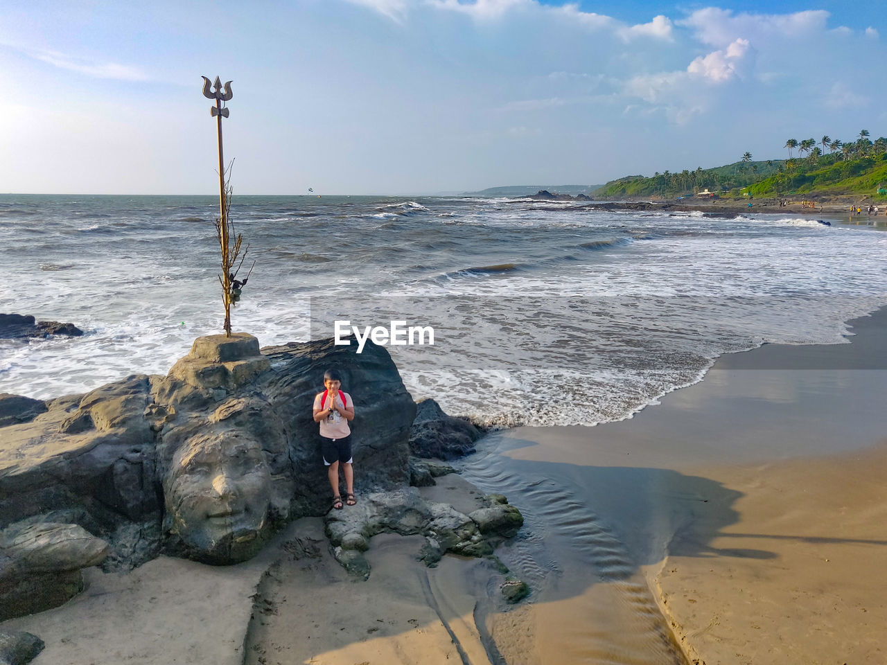 Full length of boy on rock at beach against sky