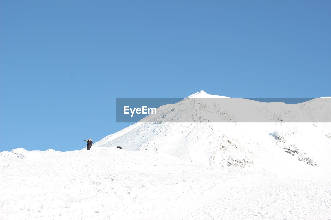 Scenic view of snowcapped mountains against clear blue sky