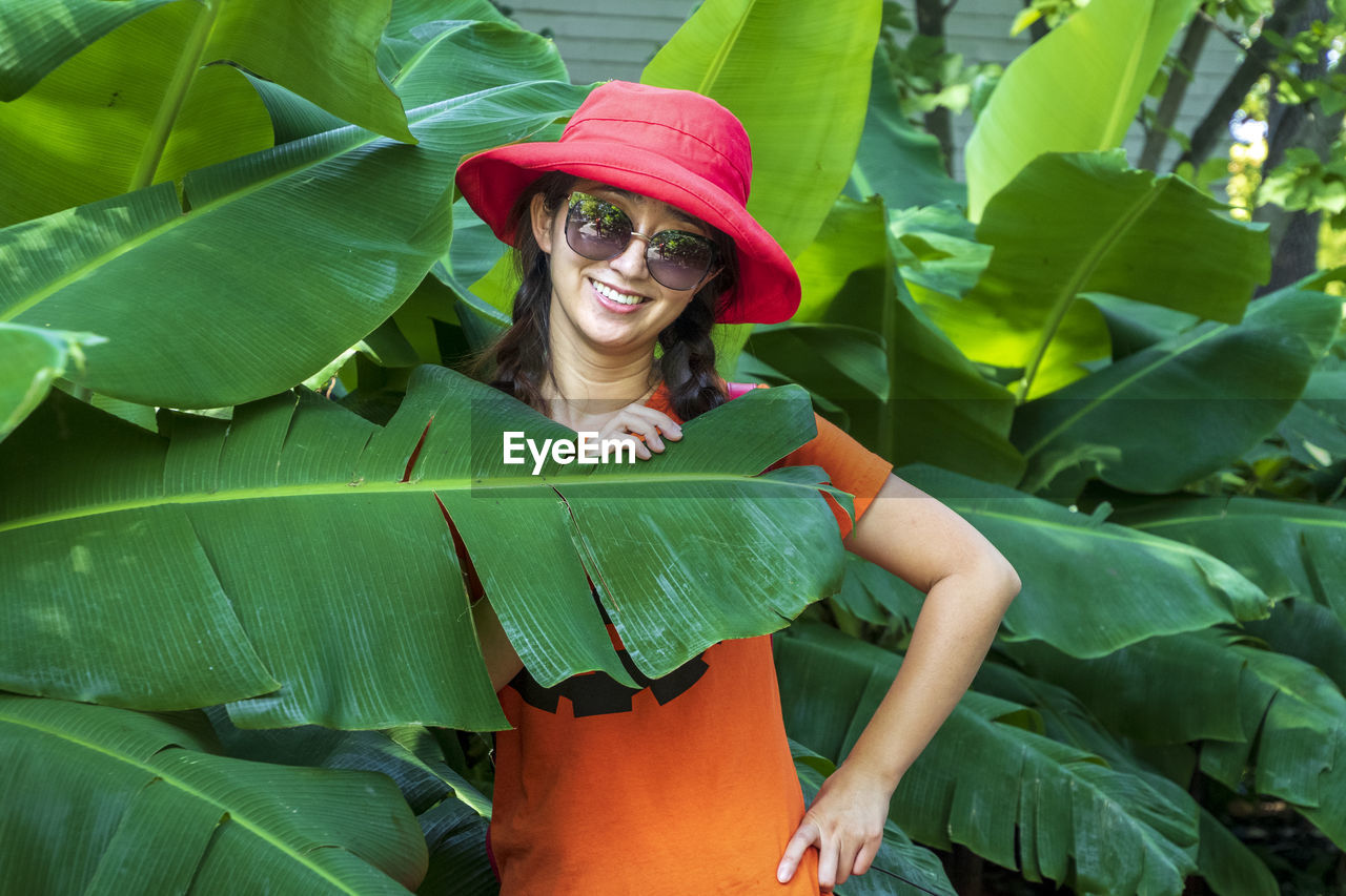 Portrait of smiling woman by plants outdoors