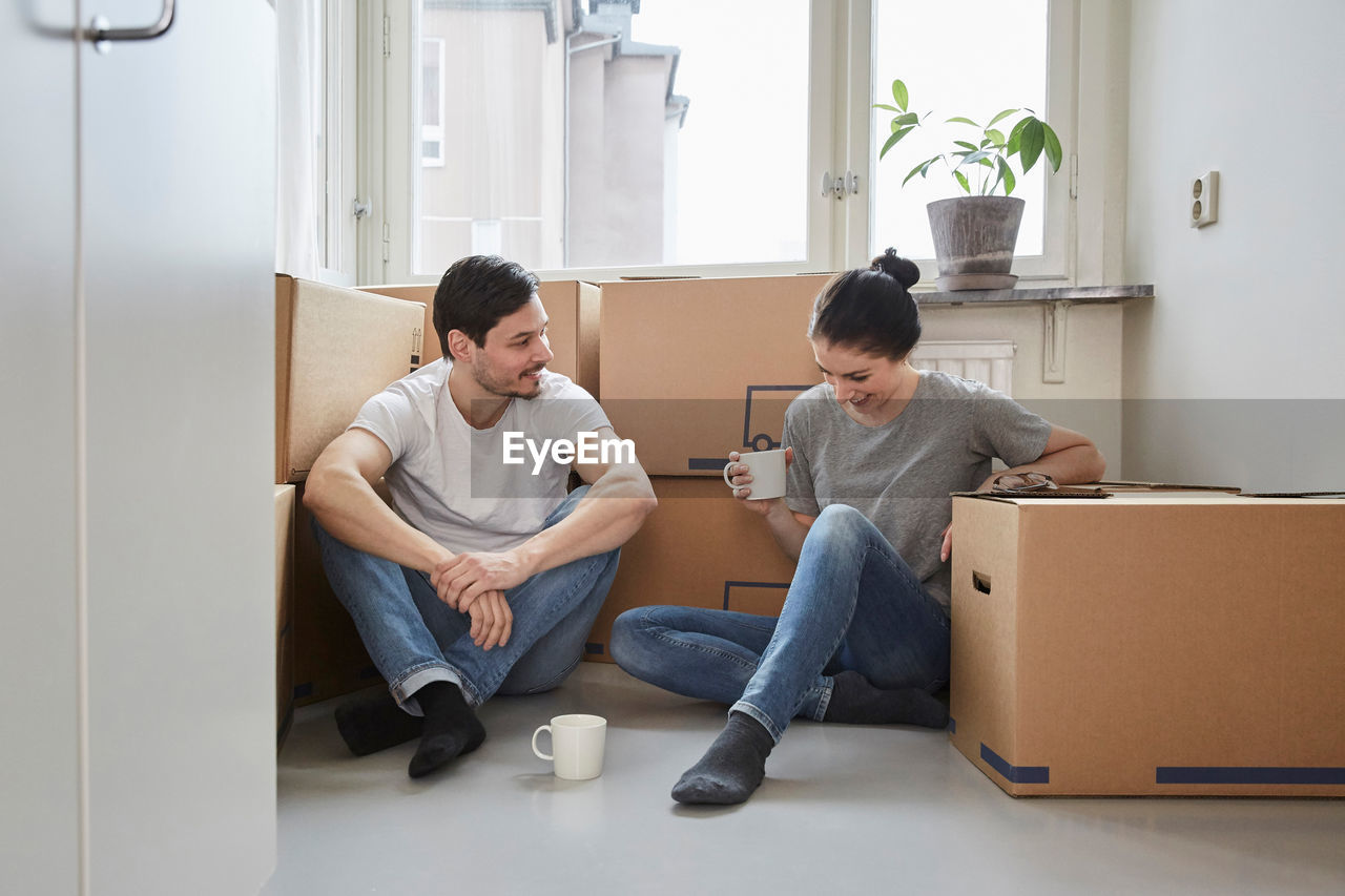 Smiling couple talking while enjoying coffee during moving house