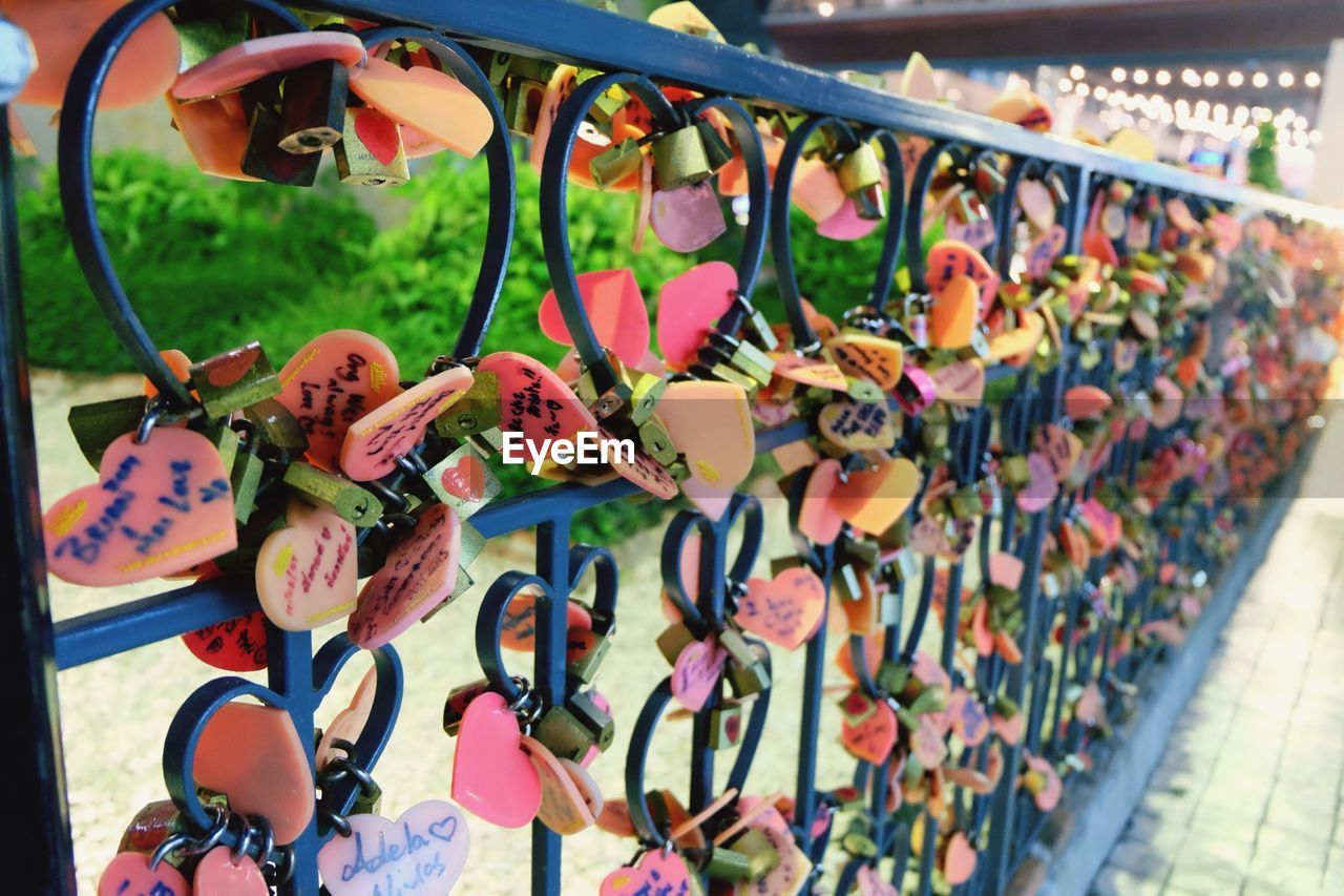 Close-up of padlocks and heart shape on railing