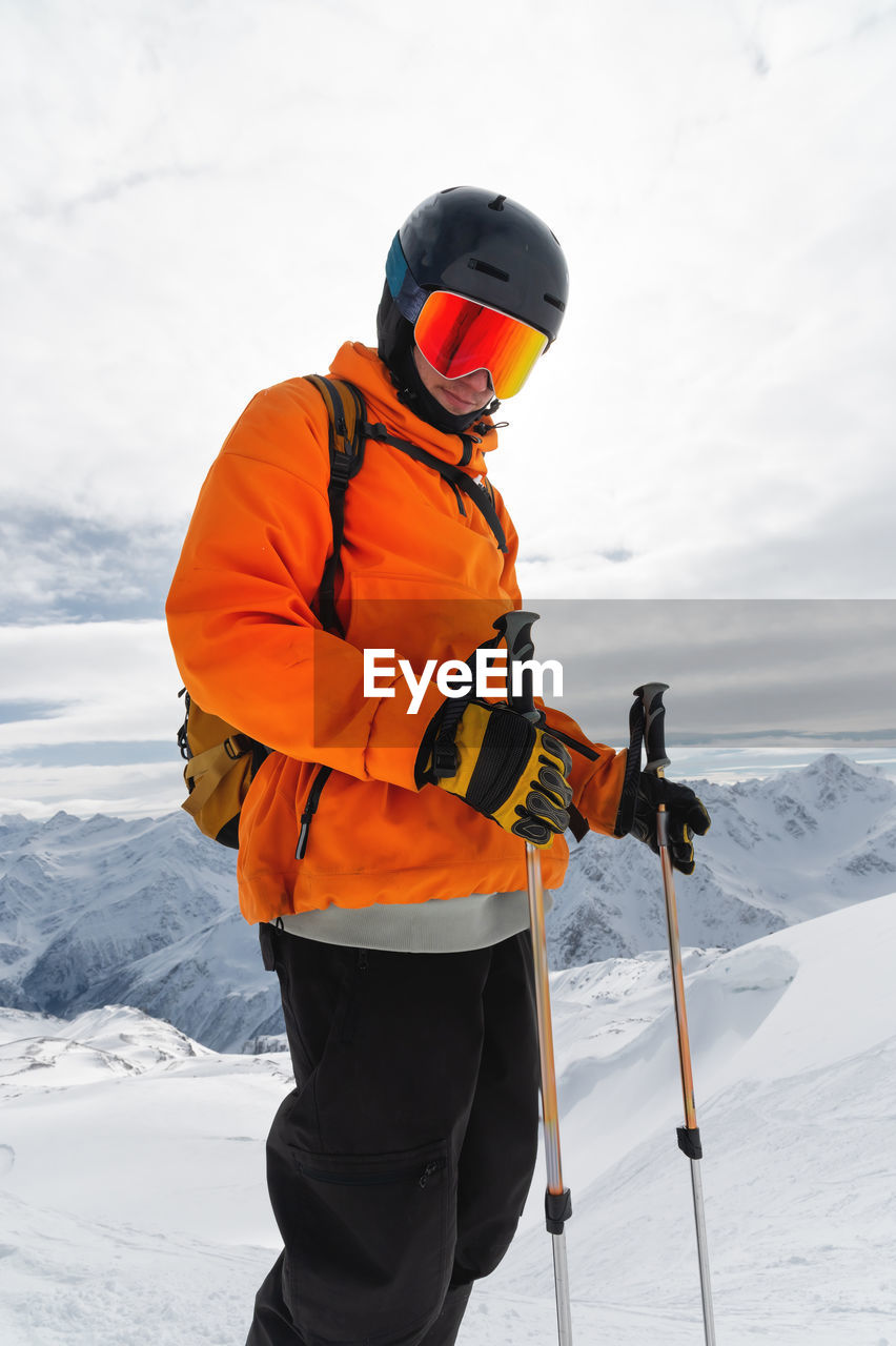 Portrait of a male skier at the top against the backdrop of epic mountains in the clouds.