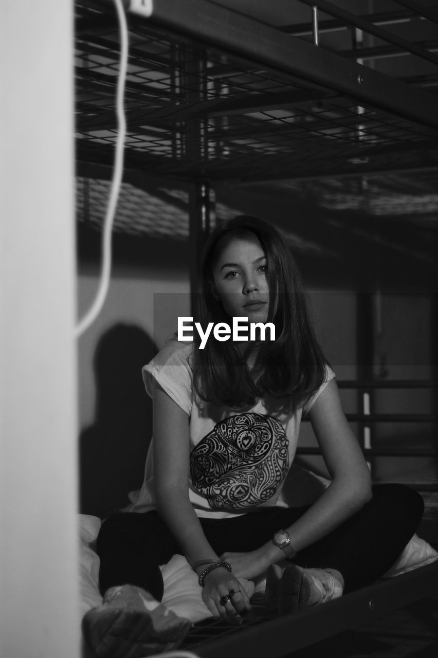 Portrait of young woman sitting on bunk bed