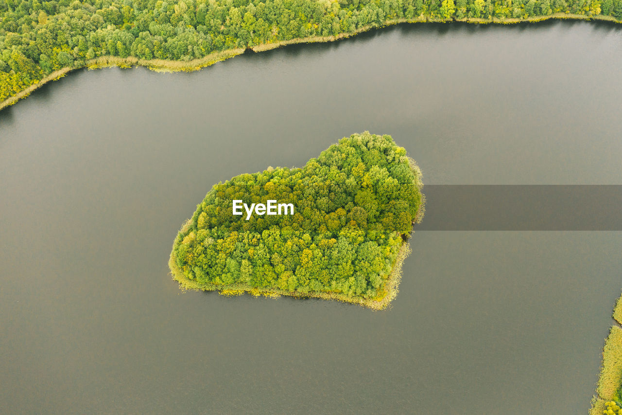 Aerial view over an island. the island is formed as a green heart.