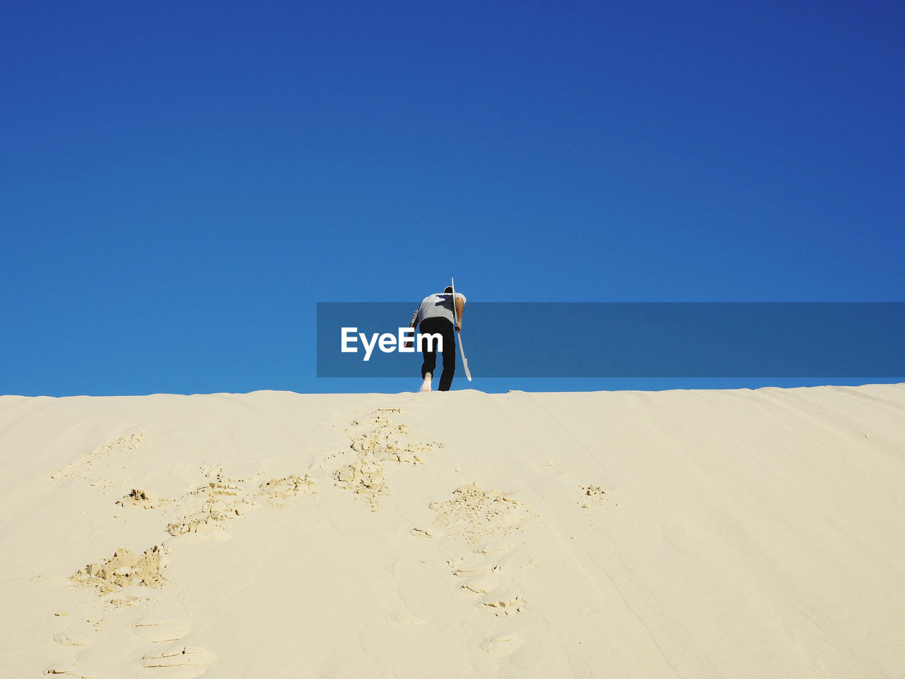 Full length of man on sand dune against clear sky