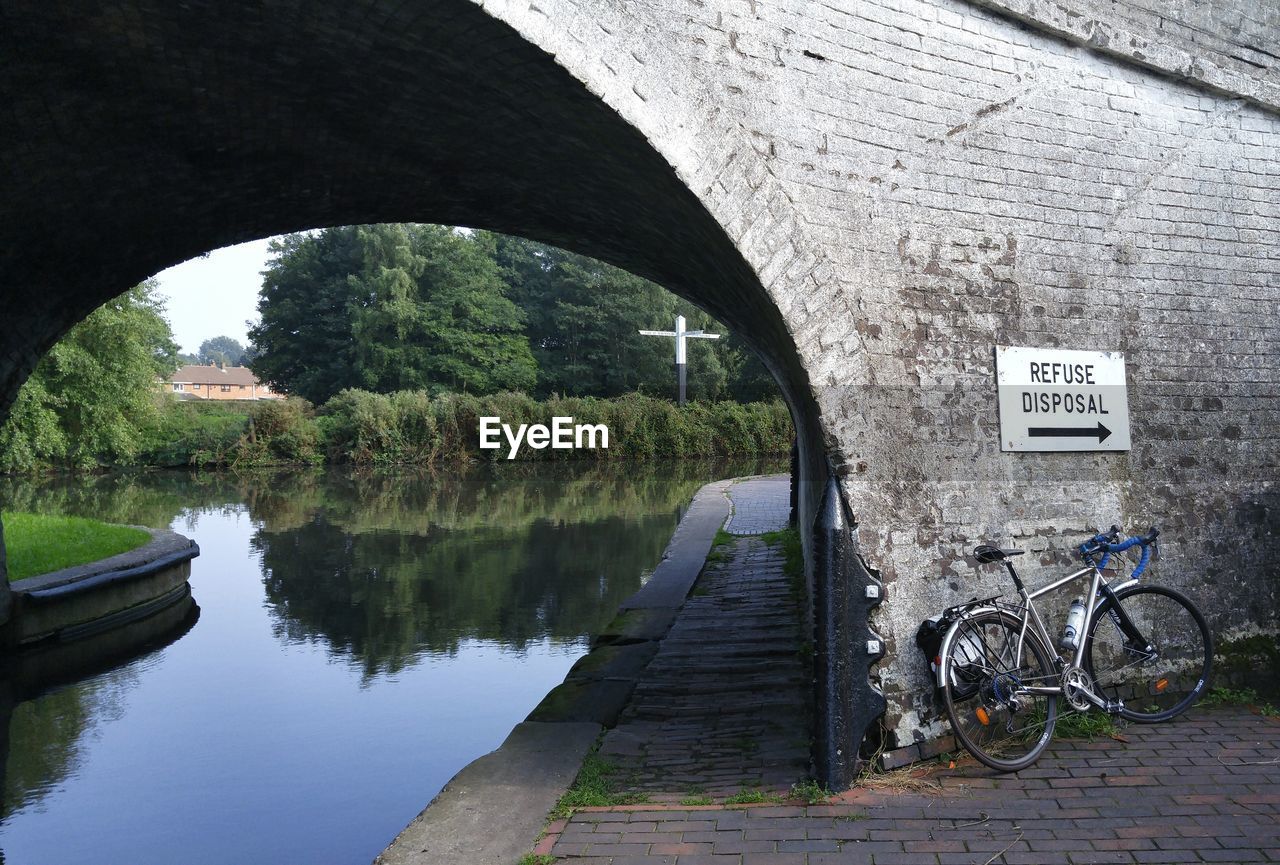 Bicycle parked by information sign on bridge over canal
