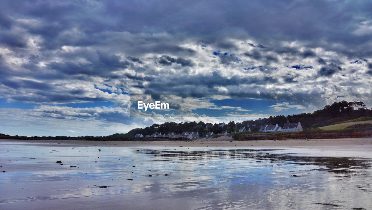 Scenic view of beach against cloudy blue sky