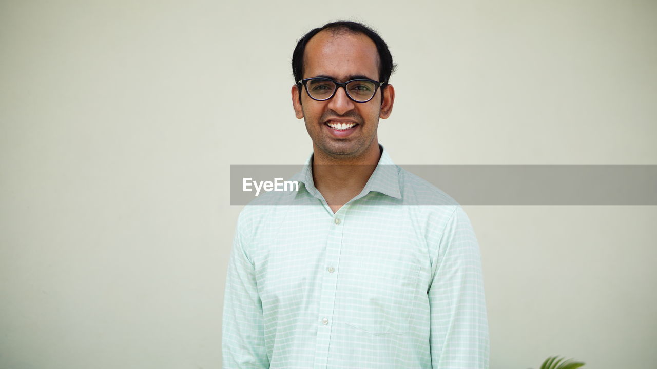 Portrait of smiling mid adult man standing against wall