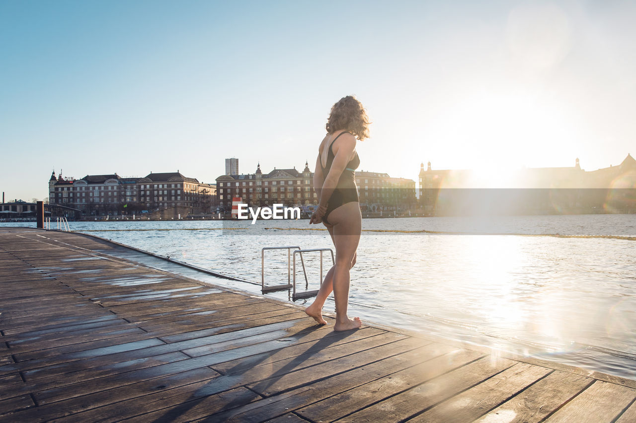 Fit woman standing alone on dock before swim in copenhagen, denmark