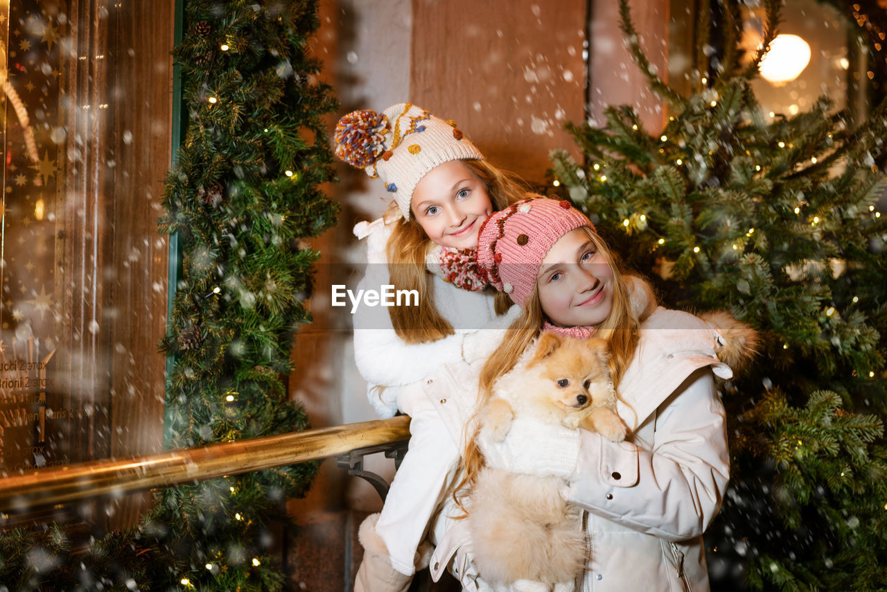 Two young girls are smiling and having fun holding spitz dog looking out