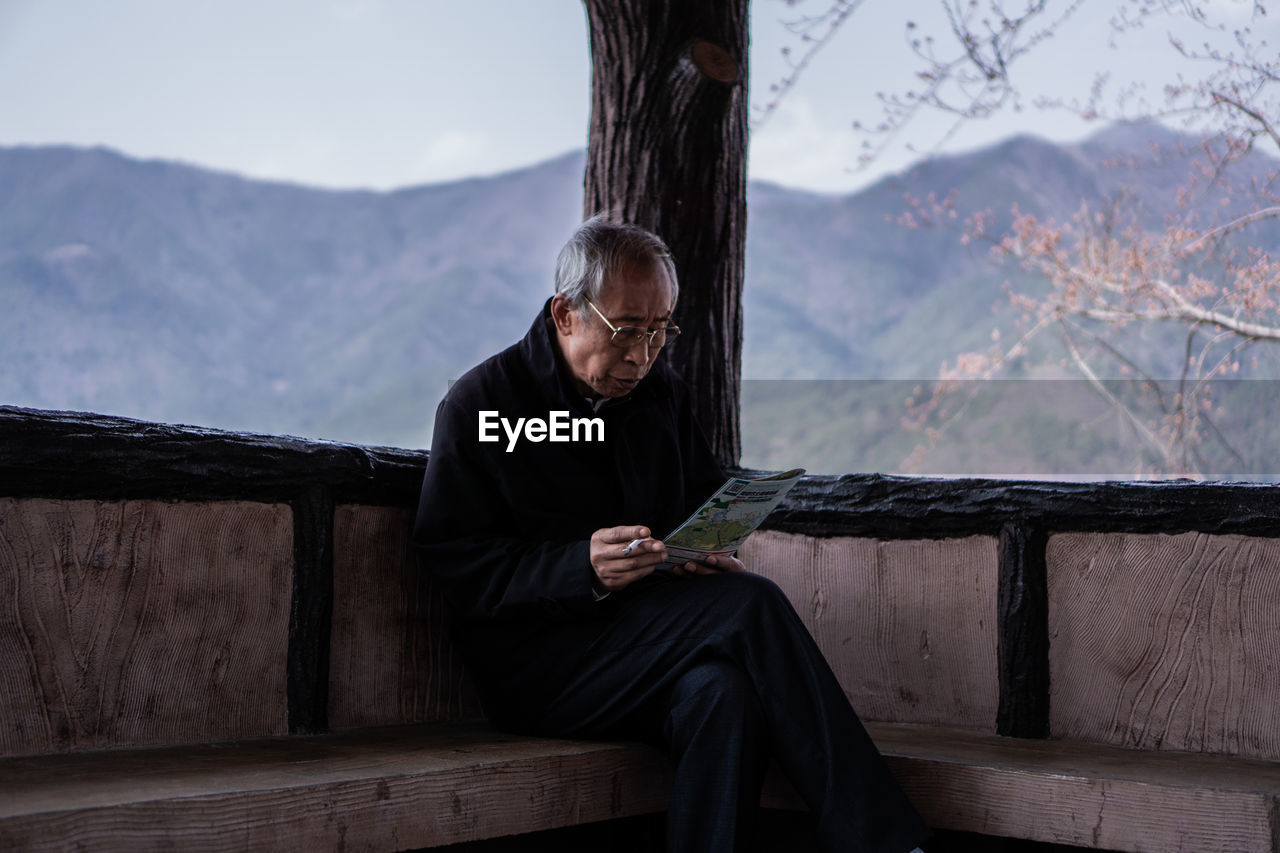 Man reading paper while sitting on seat