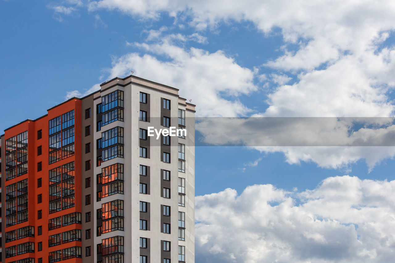 New high rise apartament building with  balcony and windows on blue sky with white clouds background