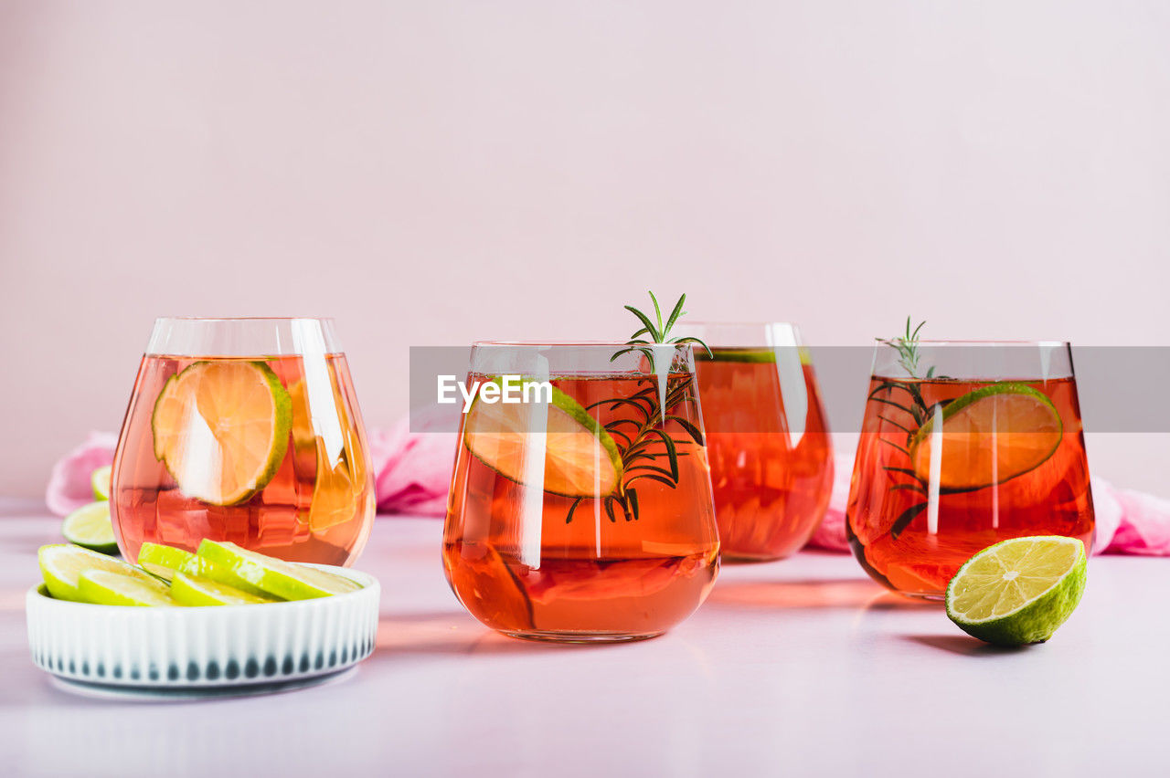 Alcoholic cocktail pink negroni with lime in glasses on table