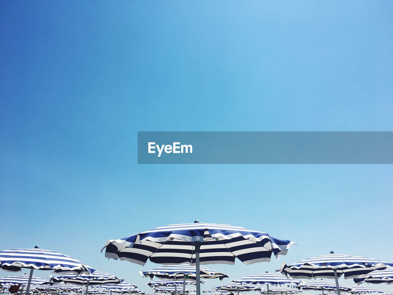 Beach umbrellas against clear blue sky