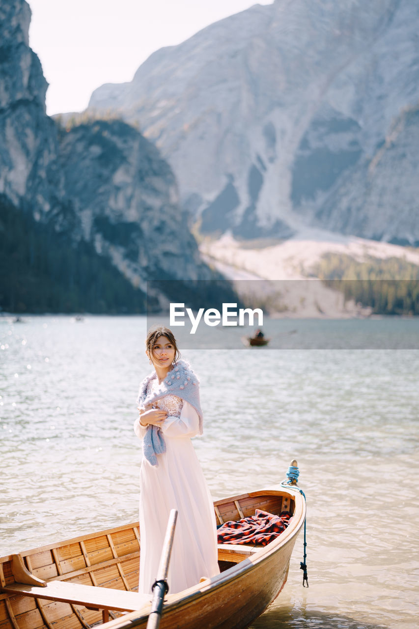 PORTRAIT OF WOMAN STANDING IN LAKE AGAINST MOUNTAINS