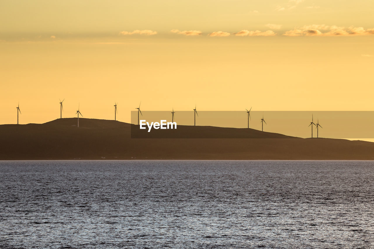 Scenic view of windmill field by the sea