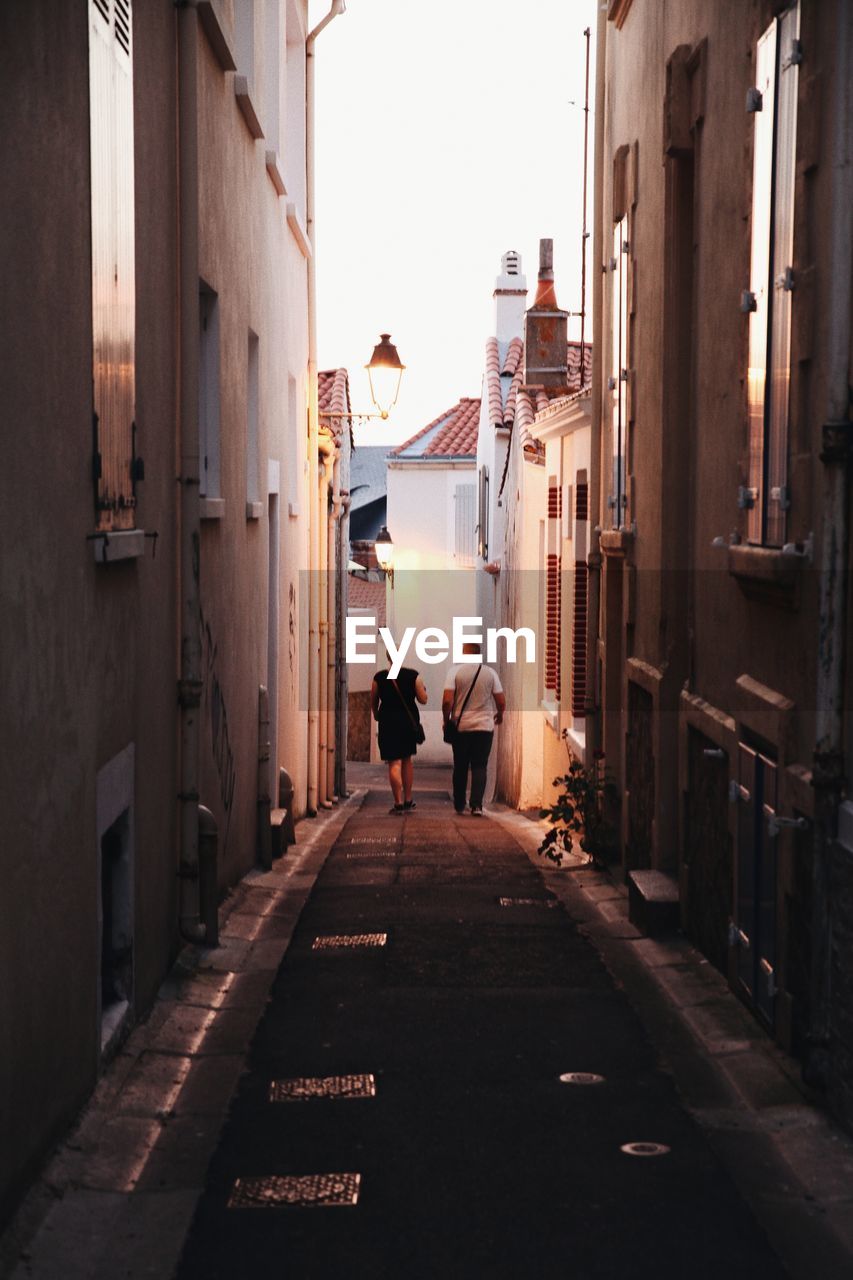 Rear view of people walking on street amidst buildings in city