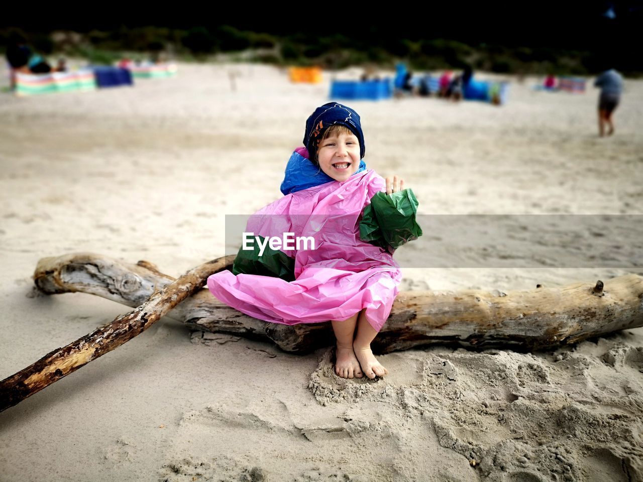 Smiling girl sitting on driftwood at beach
