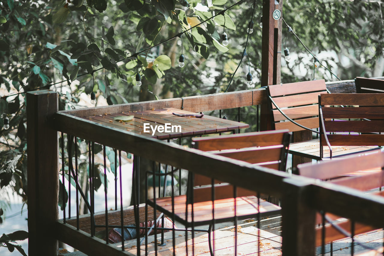 EMPTY CHAIRS AND TABLES BY TREES