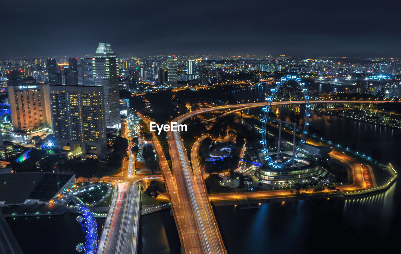 High angle view of illuminated bridge and buildings against sky at night