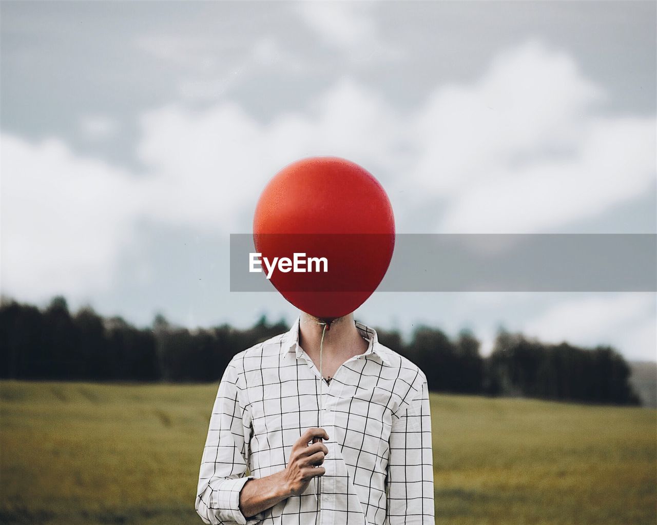 Man holding balloon on field against sky