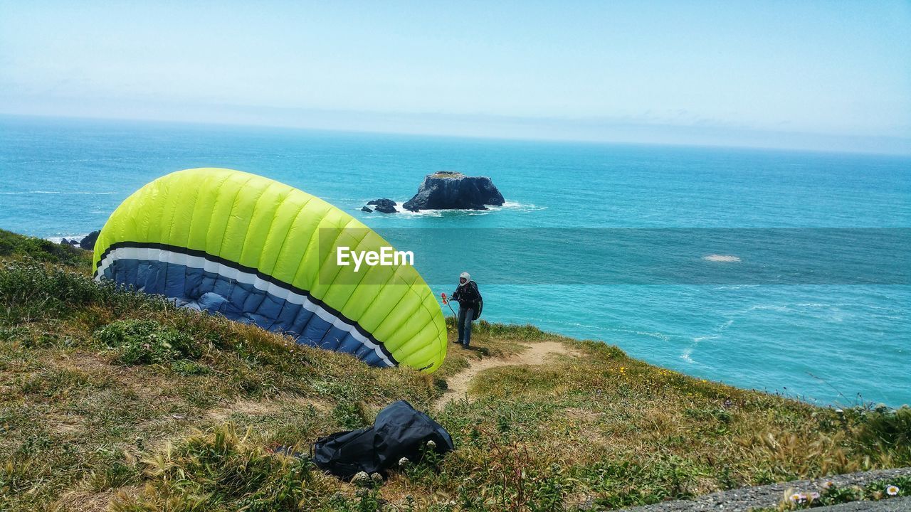 Man kiteboarding at beach against sky