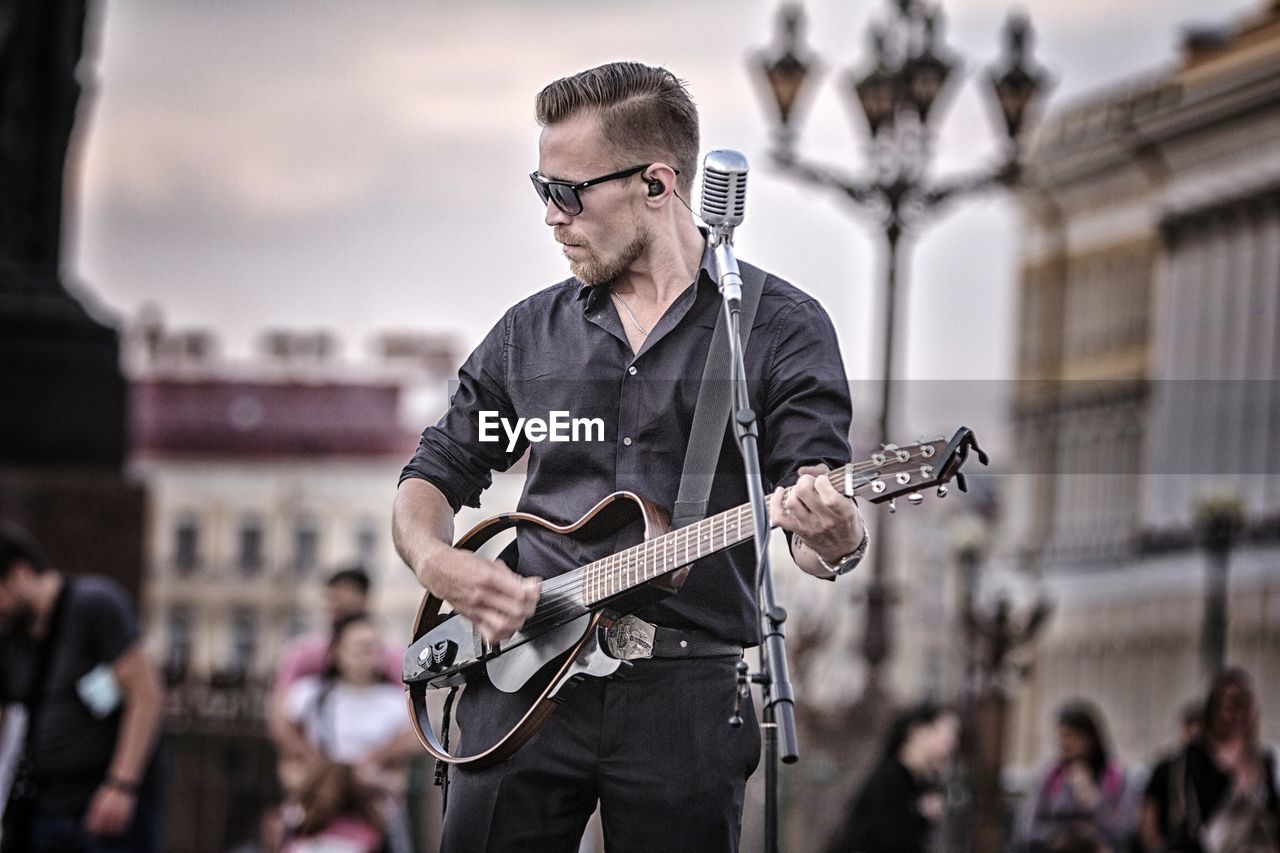 MAN PLAYING GUITAR ON CITY