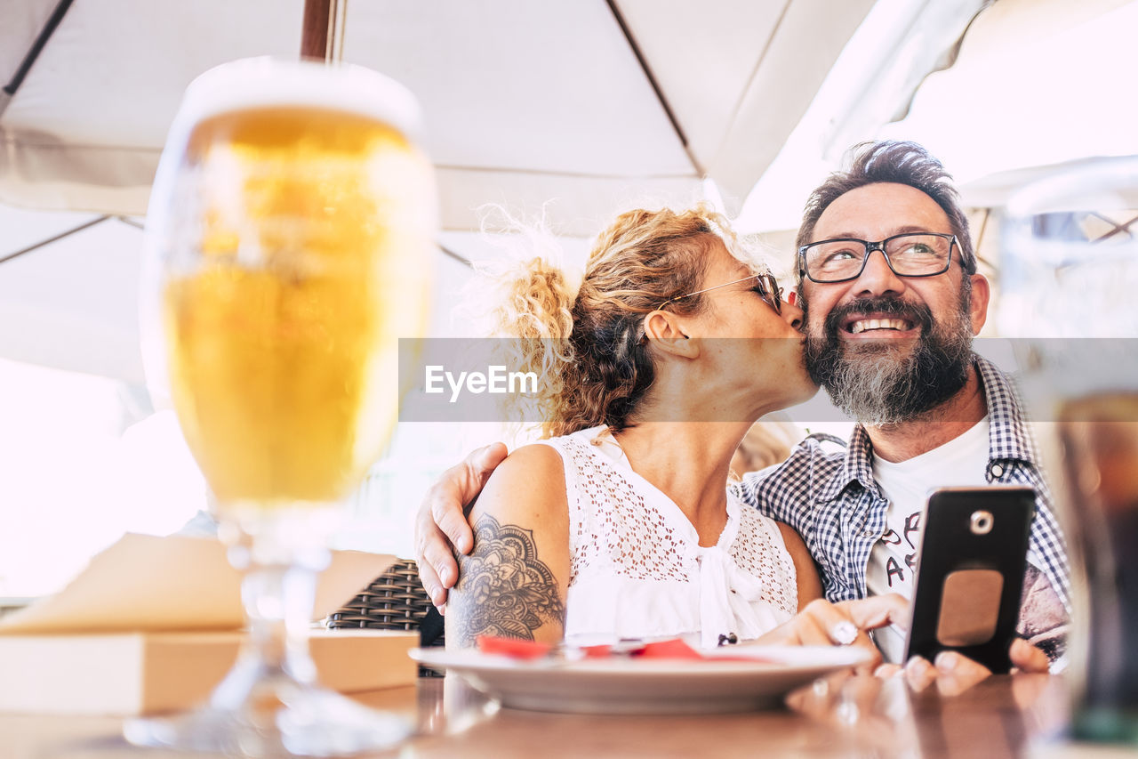 Woman kissing man while having food at table