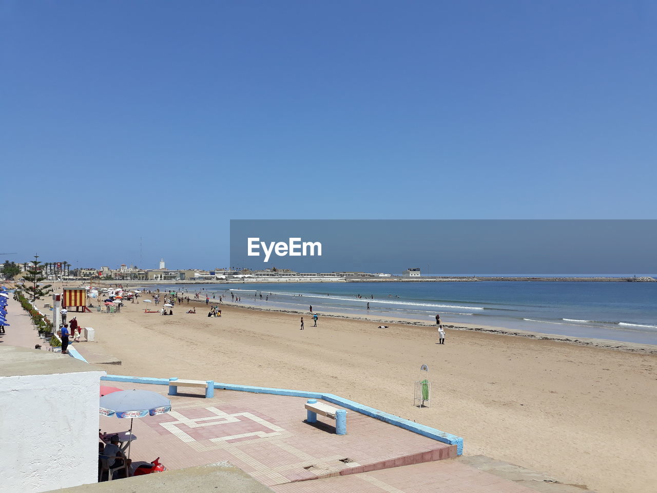 GROUP OF PEOPLE ON BEACH AGAINST CLEAR BLUE SKY