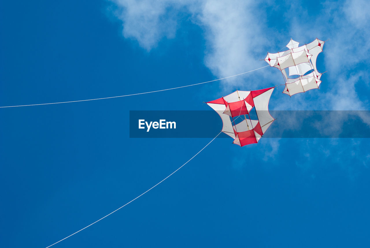 Low angle view of kites flying against sky